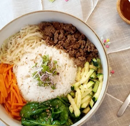 Bibimbap vu du dessus : riz, bœuf, carottes, courgette, épinards, chou