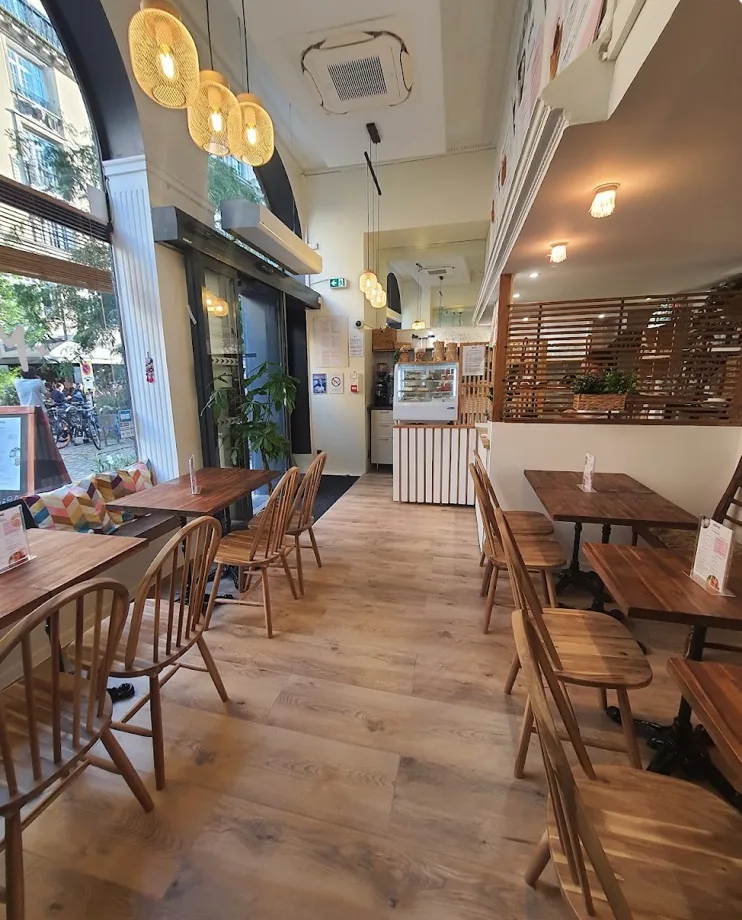 La salle de Miriné : tables en bois clair et suspensions dorées